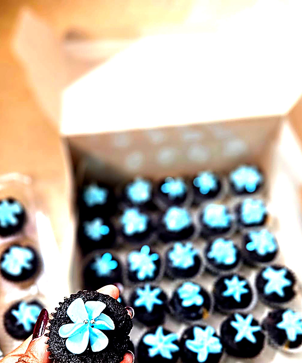 Dark chocolate cupcakes with turquoise flower frosting in a box